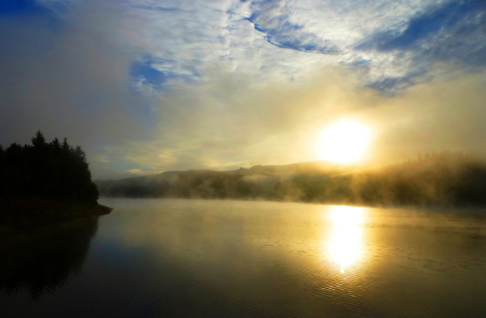 Die Sonne durchbricht den über der Talsperre liegenden zähen Nebel