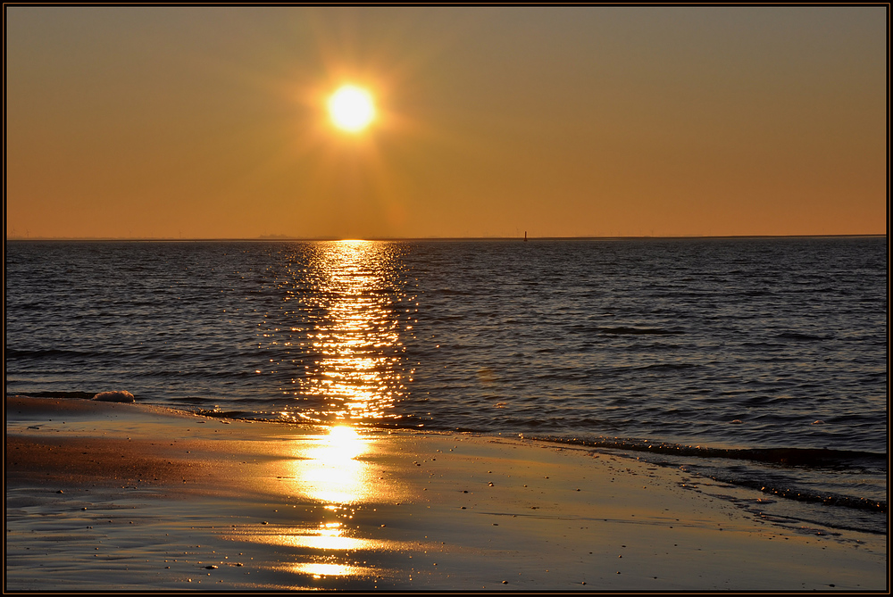 Die Sonne geht am goldenen Strand von Langeoog