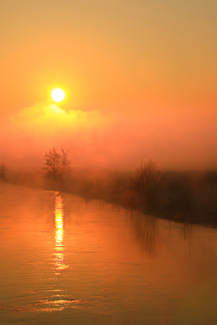 Die Sonne über Nebel und Fluss