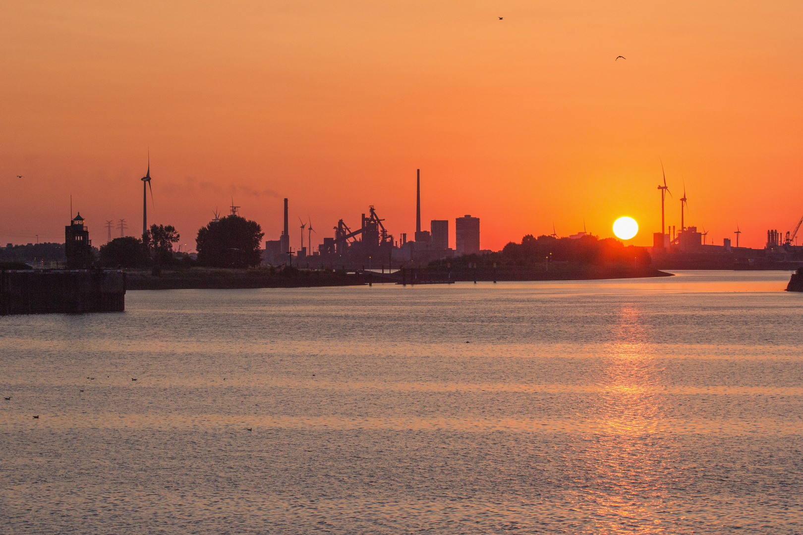 Die Sonne versinkt hinter dem Industriehafen