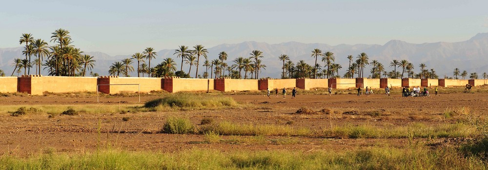 Die Stadtmauer von Marrakesch vor der Kulisse des Hohen Atlas ist das Wahrzeichen der Stadt