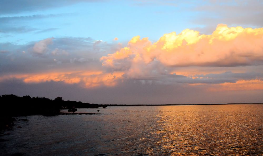 die Strahlen der untergehenden Sonne legen sich aufs Wasser