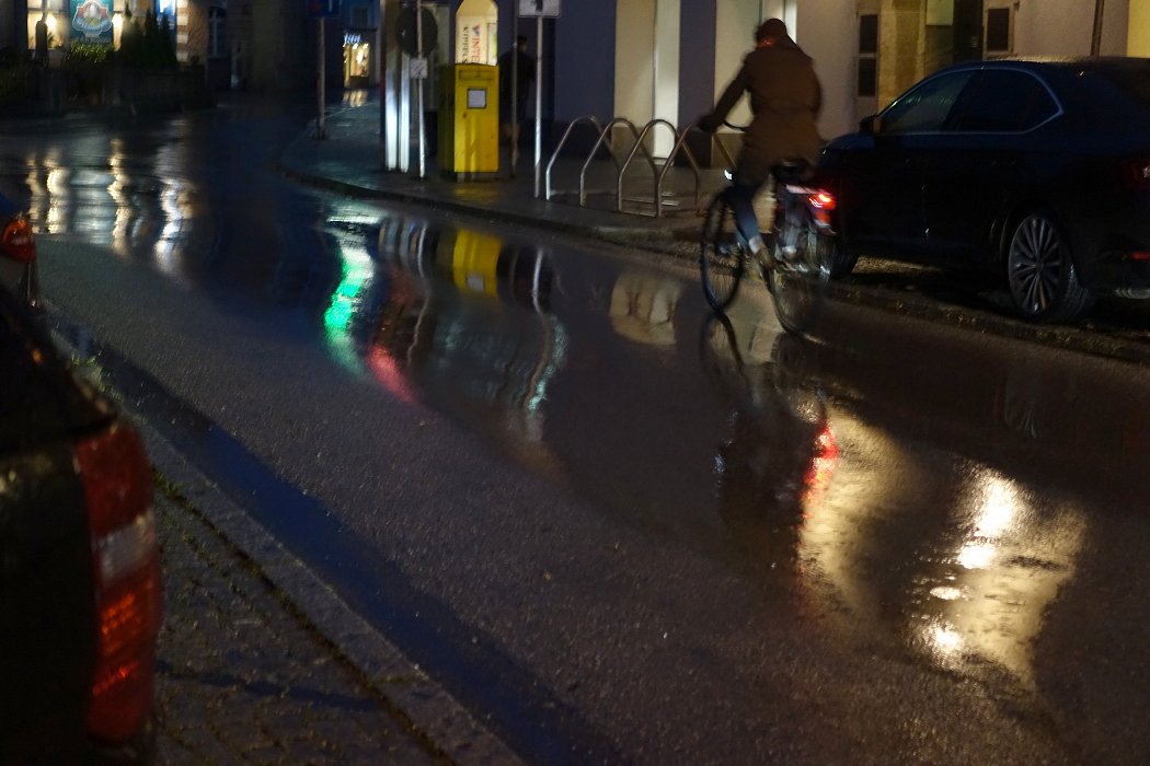 Die Straße, der Regen, das Wasser, der Radfahrer