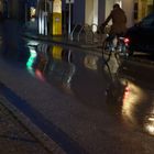Die Straße, der Regen, das Wasser, der Radfahrer