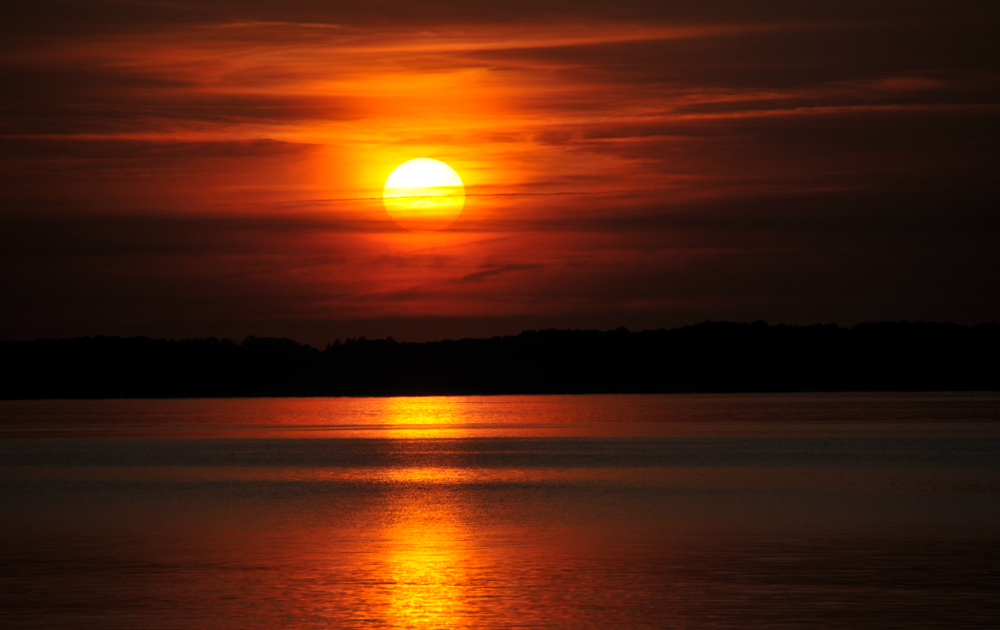 Die untergehende Sonne spiegelt sich im Meer.