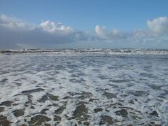 Die Wellen laufen weit über den Strand