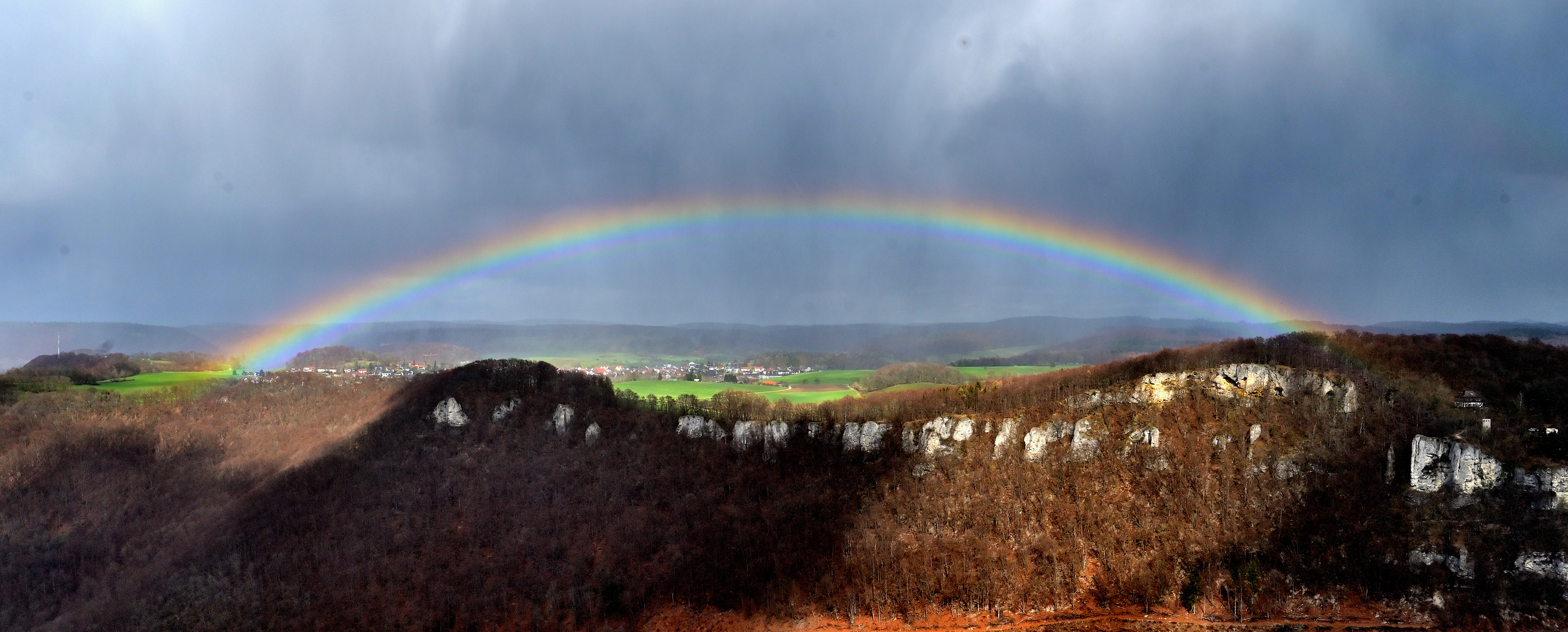 Dorf unter Panorama-Regenbogen