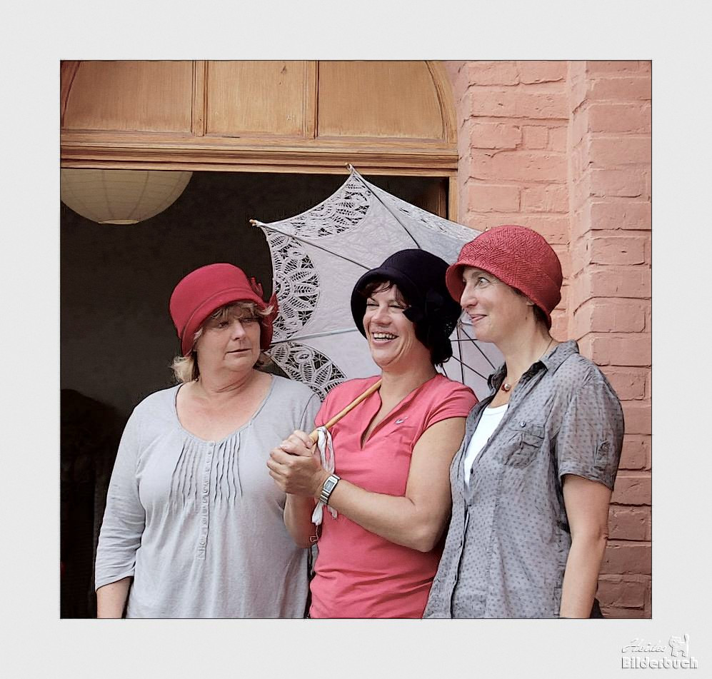 Drei Damen, drei Hüte und ein Schirm