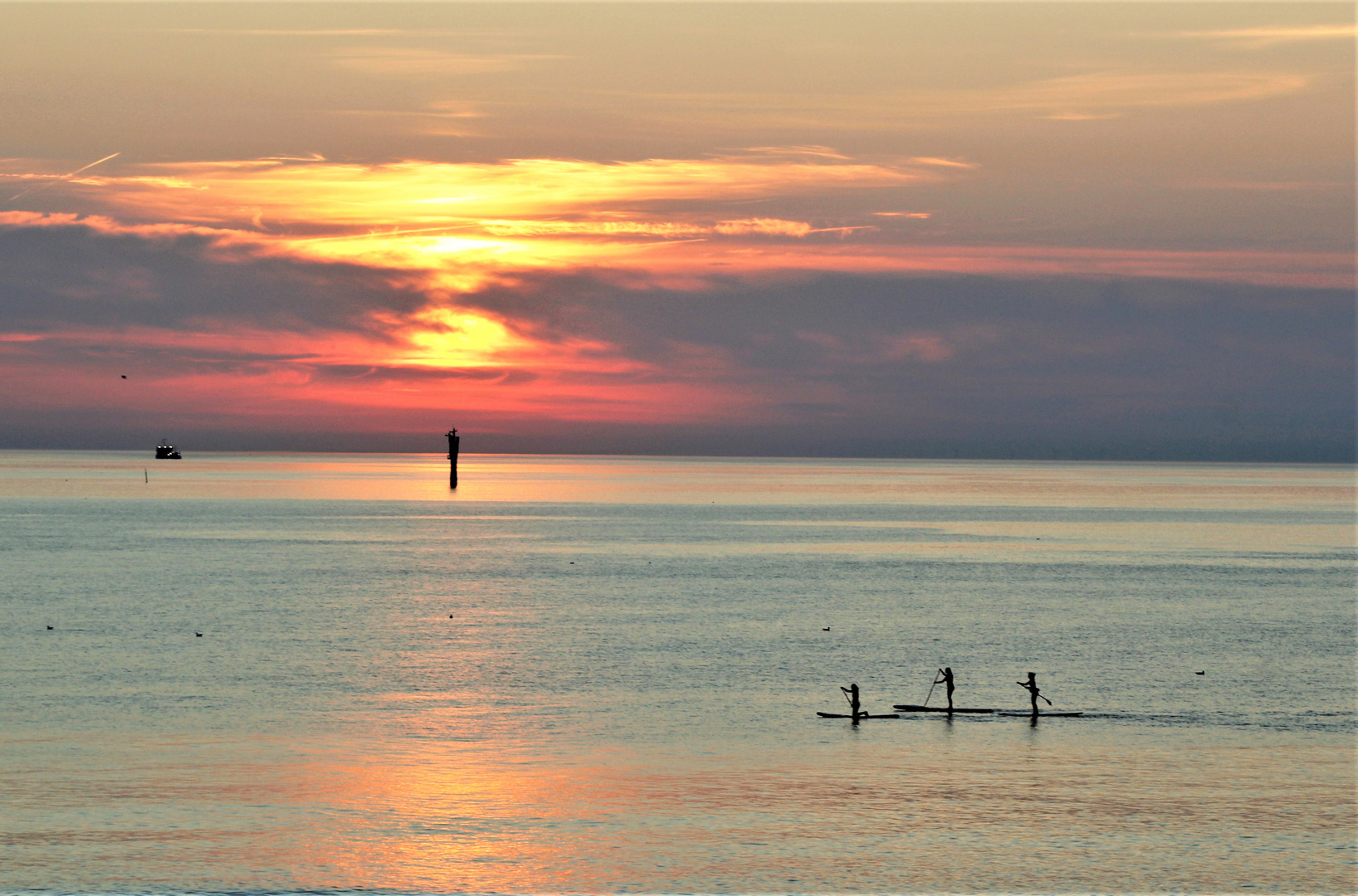 Drei Paddler auf dem Meer.