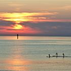 Drei Paddler auf dem Meer.