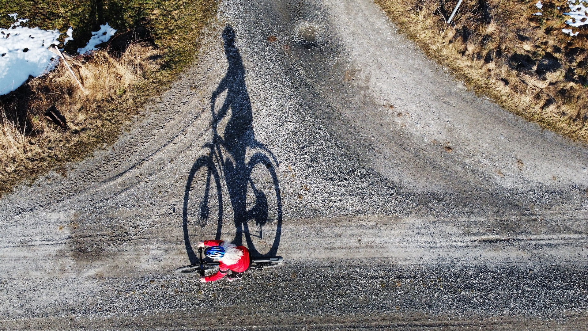 Drohnenaufnahme von einer Radfahrerin mit großem Schatten