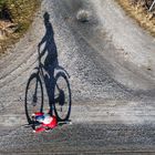 Drohnenaufnahme von einer Radfahrerin mit großem Schatten