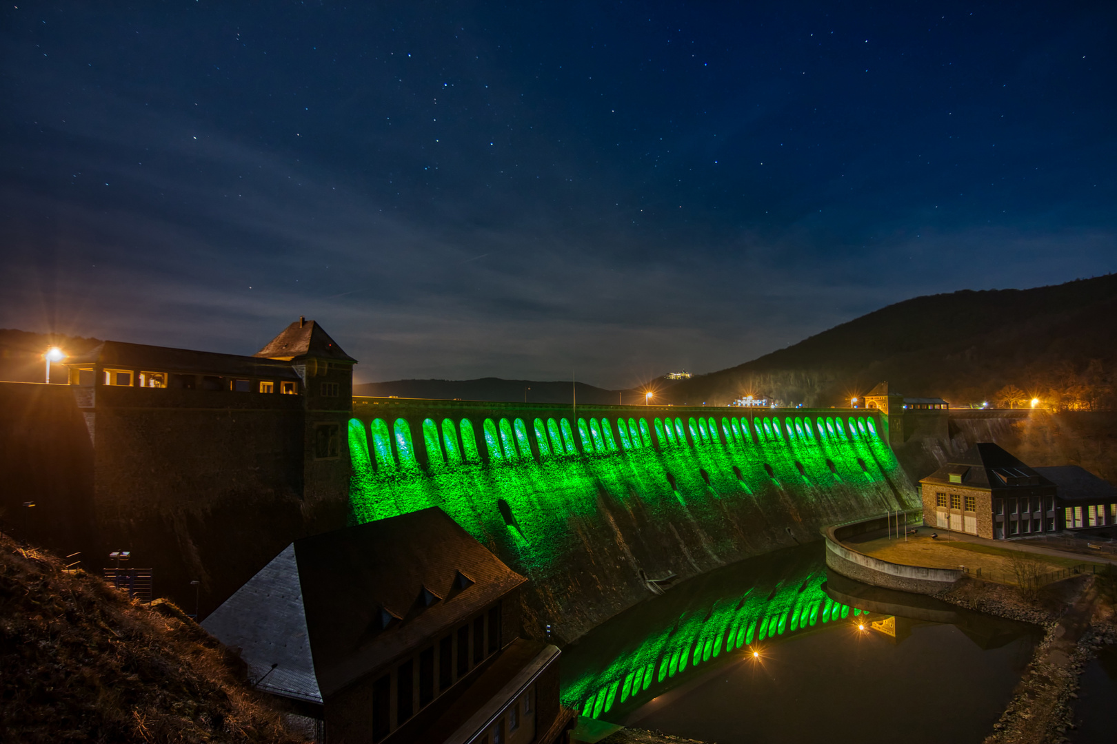 Edertalsperre in grüner Illumination mit Sternenhimmel.