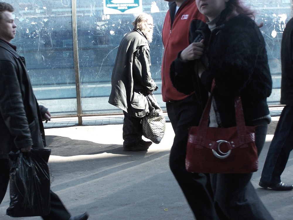 Eilende Passanten vor überbelichtetem altem Mann mit Einkaufstasche
