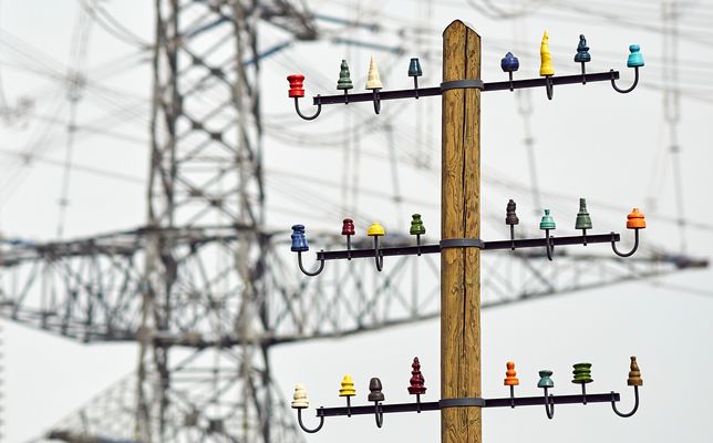 Ein alter Telegraphenmast vor einem Strommasten, so nah zusammen stehen sie nicht,…