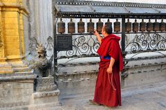 Ein buddhistischer Mönch beim Drehen der Gebetsmühlen am Stupa von Swayambhunath
