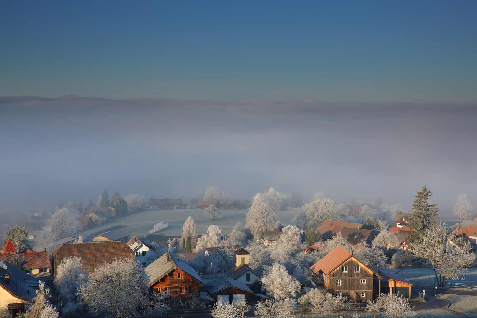 Ein Dorf erstrahlt über dem Nebel