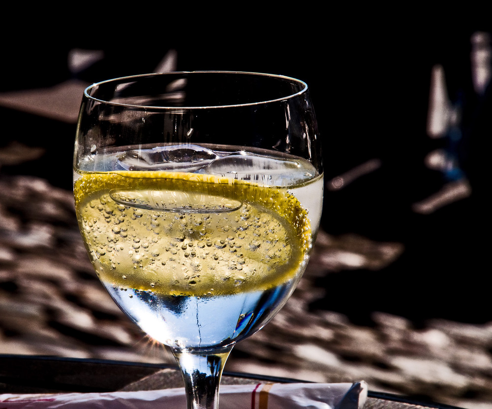 Ein Glas Wasser mit einer Scheibe Zitrone und drei Eisstücke