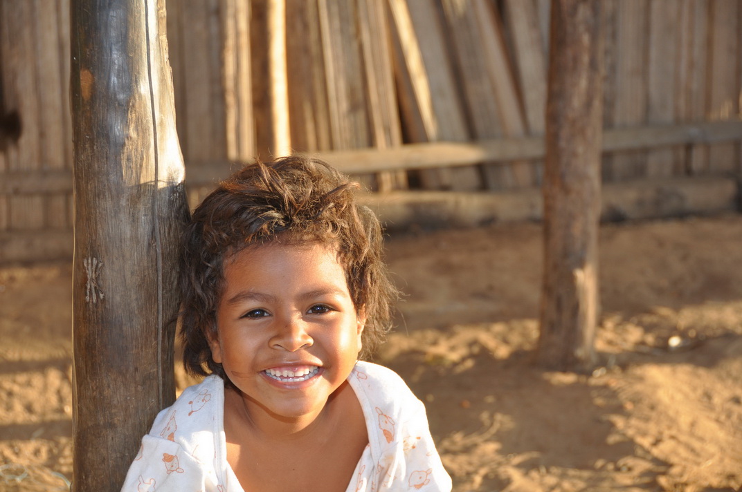 Ein Kind mit einem schönen Lächeln auf dem Land mit dem Haus in Nord Madagaskar