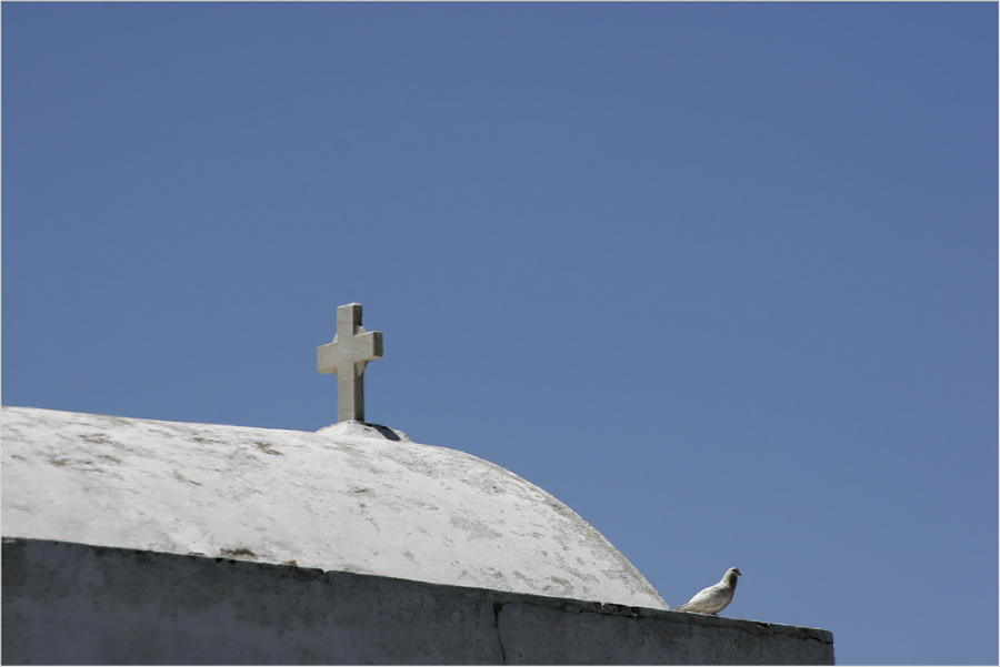 ein Kreuz, eine Taube und der blaue Himmel über Mykonos