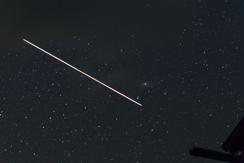 ein Satelit auf seiner Umlaufbahn mit Andromeda im Hintergrund