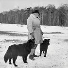 Ein Schaefer im Winter mit seinen zwei Hunden