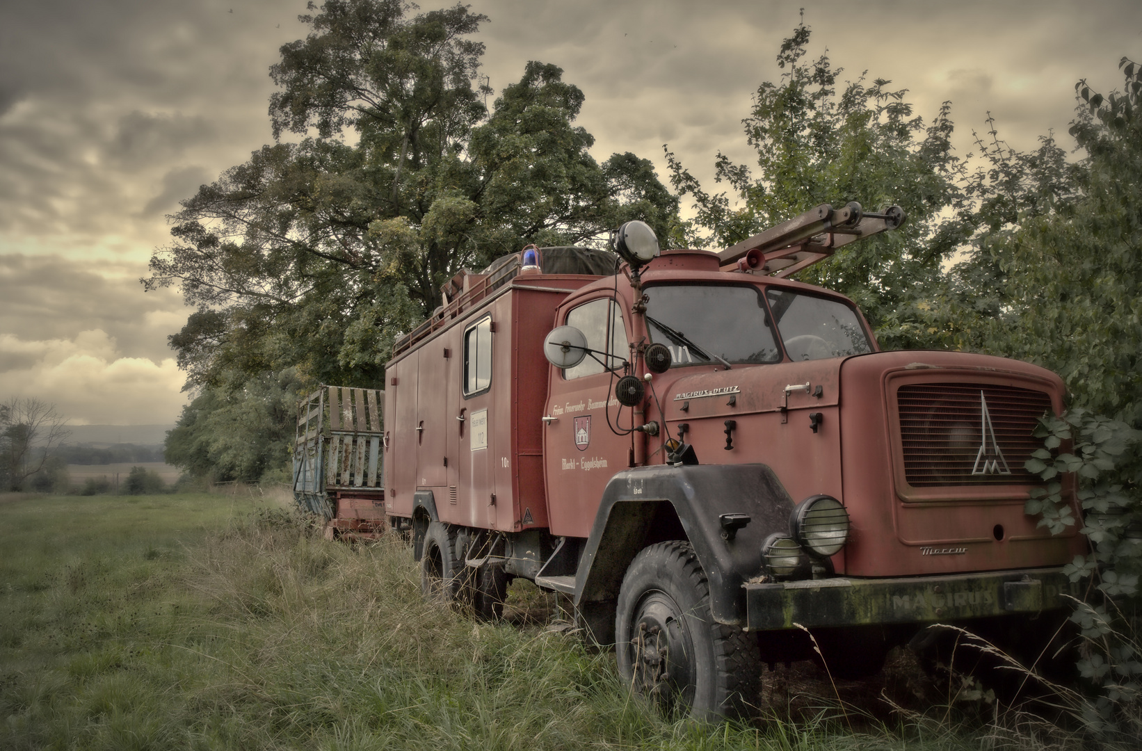 ein seltsames Gespann - altes Feuerwehrauto und Ladewagen auf grüner Wiese (2)