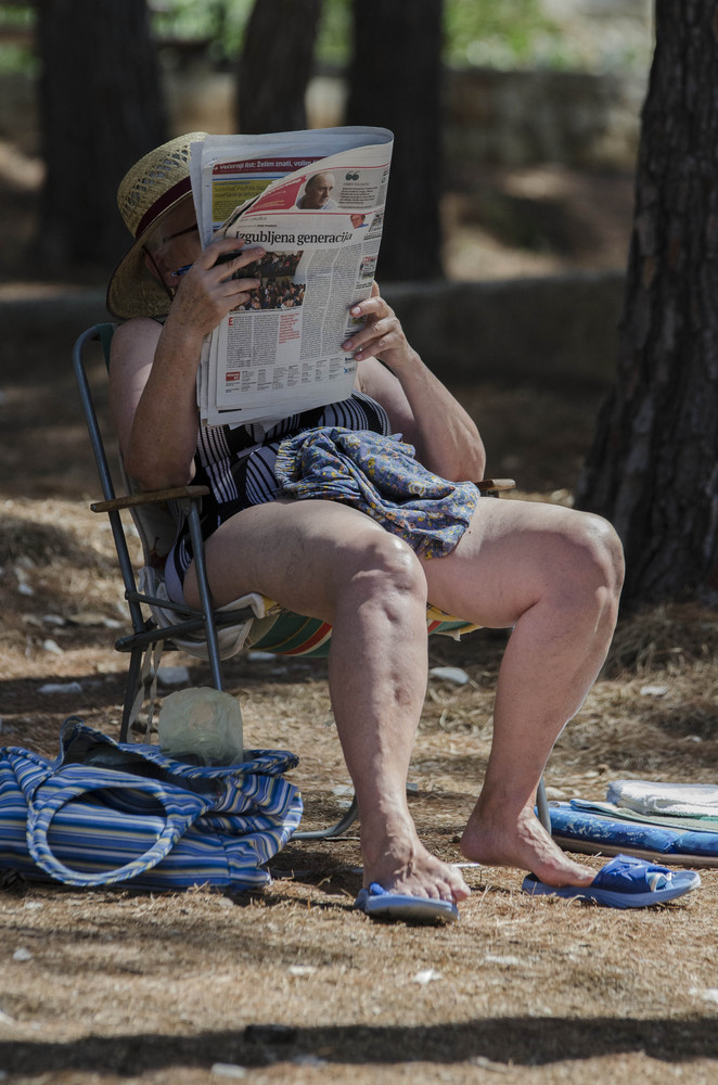 Ein Tag am Strand: Zeitungsleserin