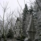 ein verschneites Bauernhaus hinterm hohen Zaun