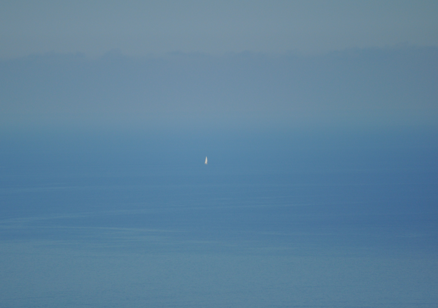 Ein weißes Segel im Nebel des Meeres blau…