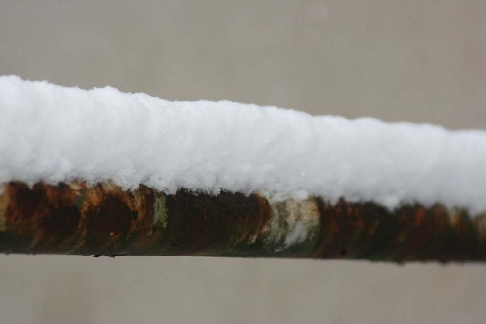 Eine alte Stange im Winter, bedeckt mit ein paar cm dickem Schnee