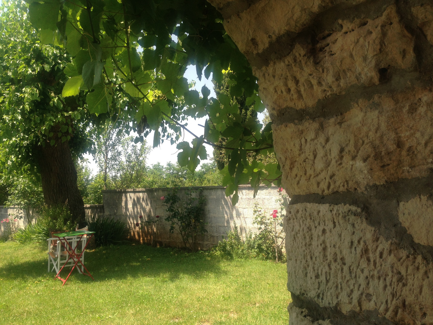 EINEN SCHATTENPLATZ UNTER DEN KÜHLENDEN MAUERN DES HAUSES MIT AUSBLICK AUF DEN GARTEN