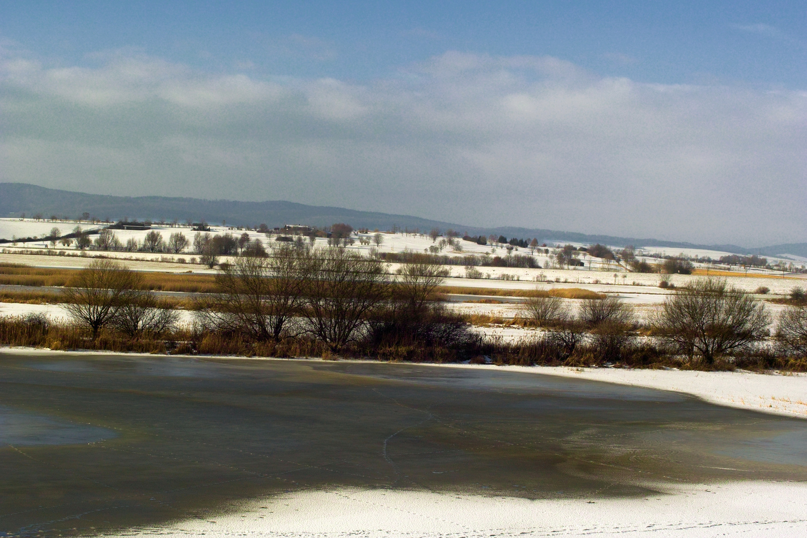 Eingefrorenes Leinerückhaltebecken mit Blick auf den Golfplatz Immensen/ Einbeck.