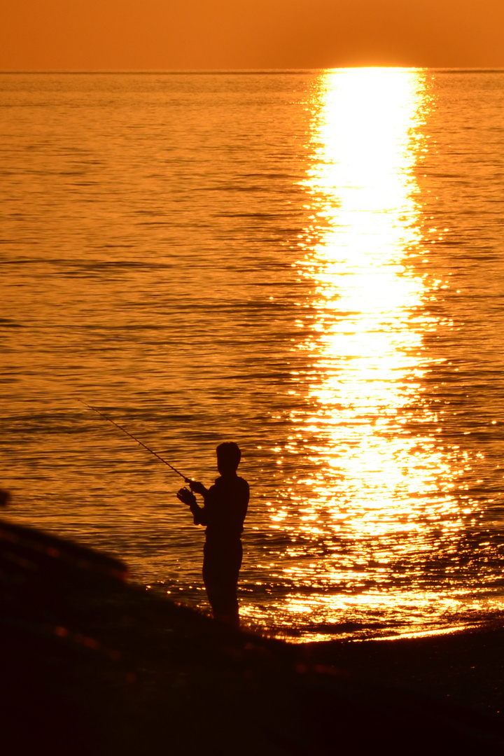 einsamer Angler bei Sonnenuntergang mitten im November