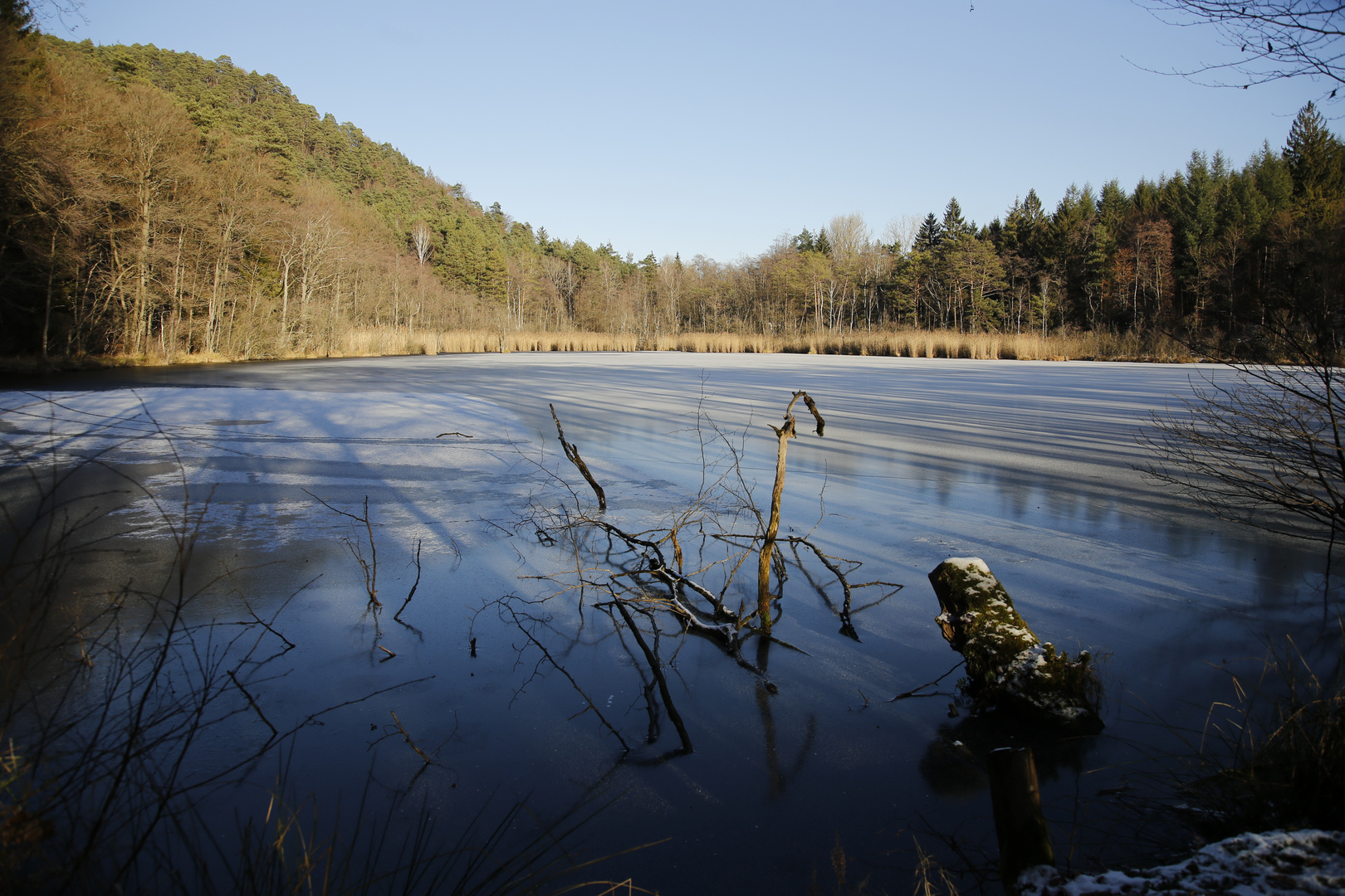 Eis bedeckt den Weiher an einem sonnigen Wintertag