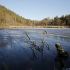 Eis bedeckt den Weiher an einem sonnigen Wintertag