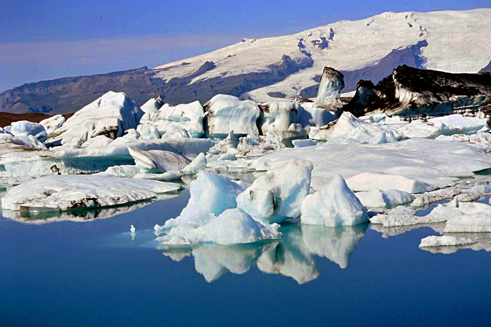 Eis bricht vom Gletscher ab und schmilzt im See langsam dahin.