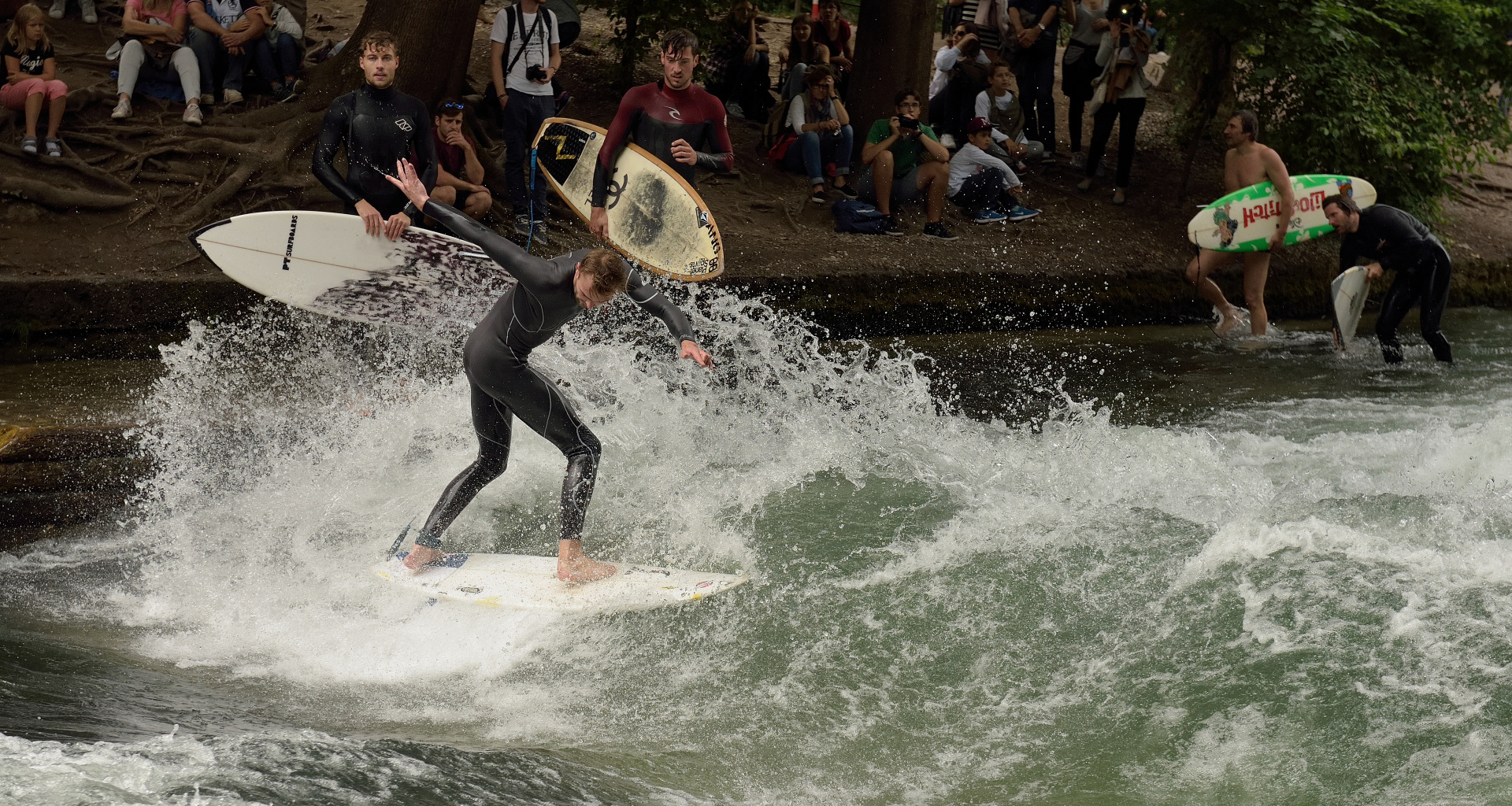 Eisbachsurfer und Eisbachwelle im Englischen Garten in München. Hier trifft sich..