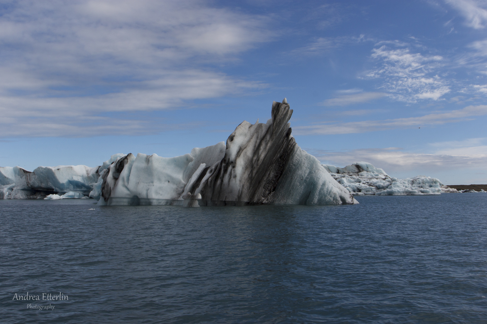 Eisberg mit Asche in Gletscherlagune
