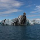 Eisberg mit Asche in Gletscherlagune