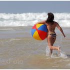 "Endlich Urlaub" - Junge Frau mit buntem Wasserball läuft Meereswellen entgegen