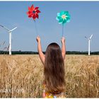 "Energiewende" - Kleines langhaariges Mädchen mit Windspiel vor Windrädern