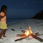 Enfant se réchauffant près d'un feu sur la plage