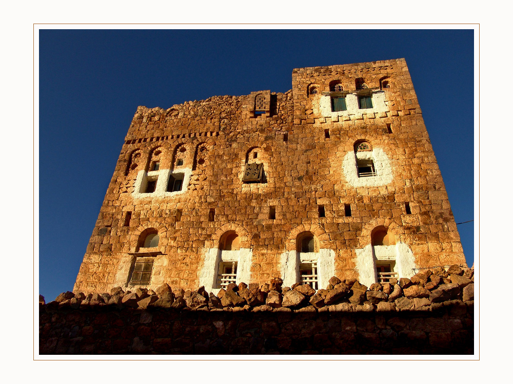 erste Sonnenstrahlen auf ein Steinhaus in Al Shaharah