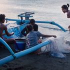 Family picking the fish from the net at dusk