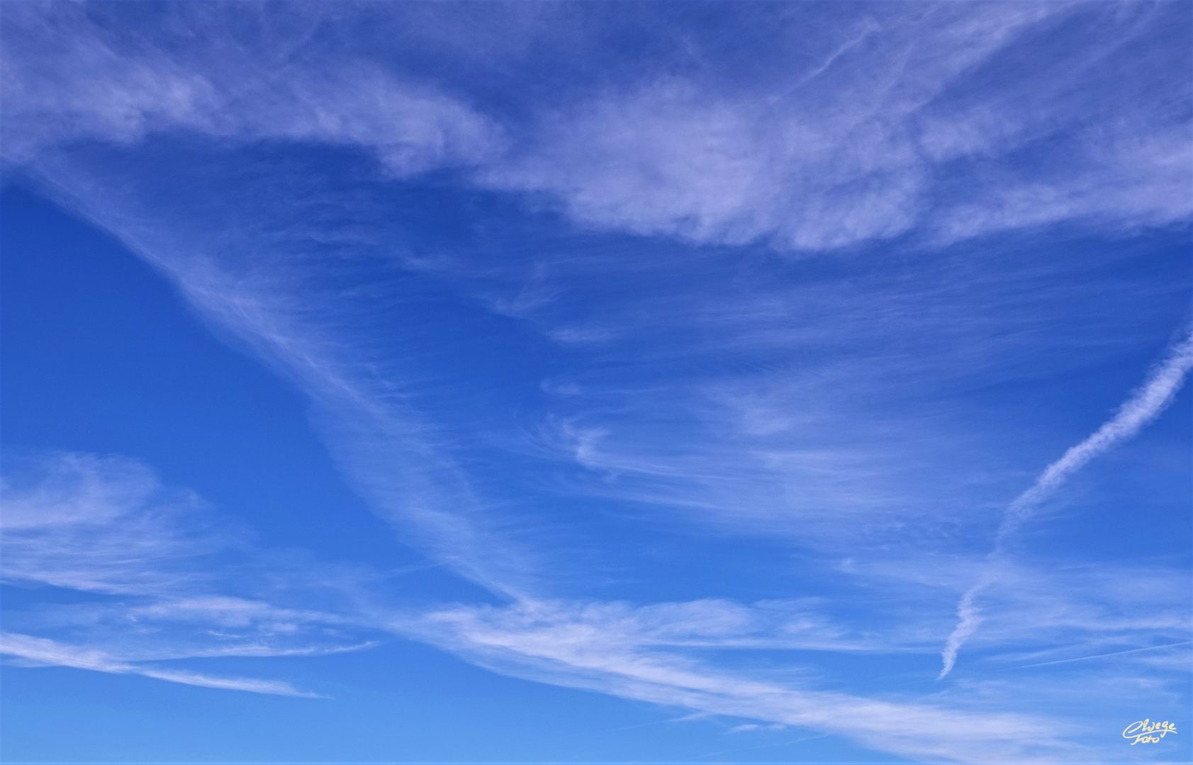 Feine weiße Federwolken am blauen Himmel.