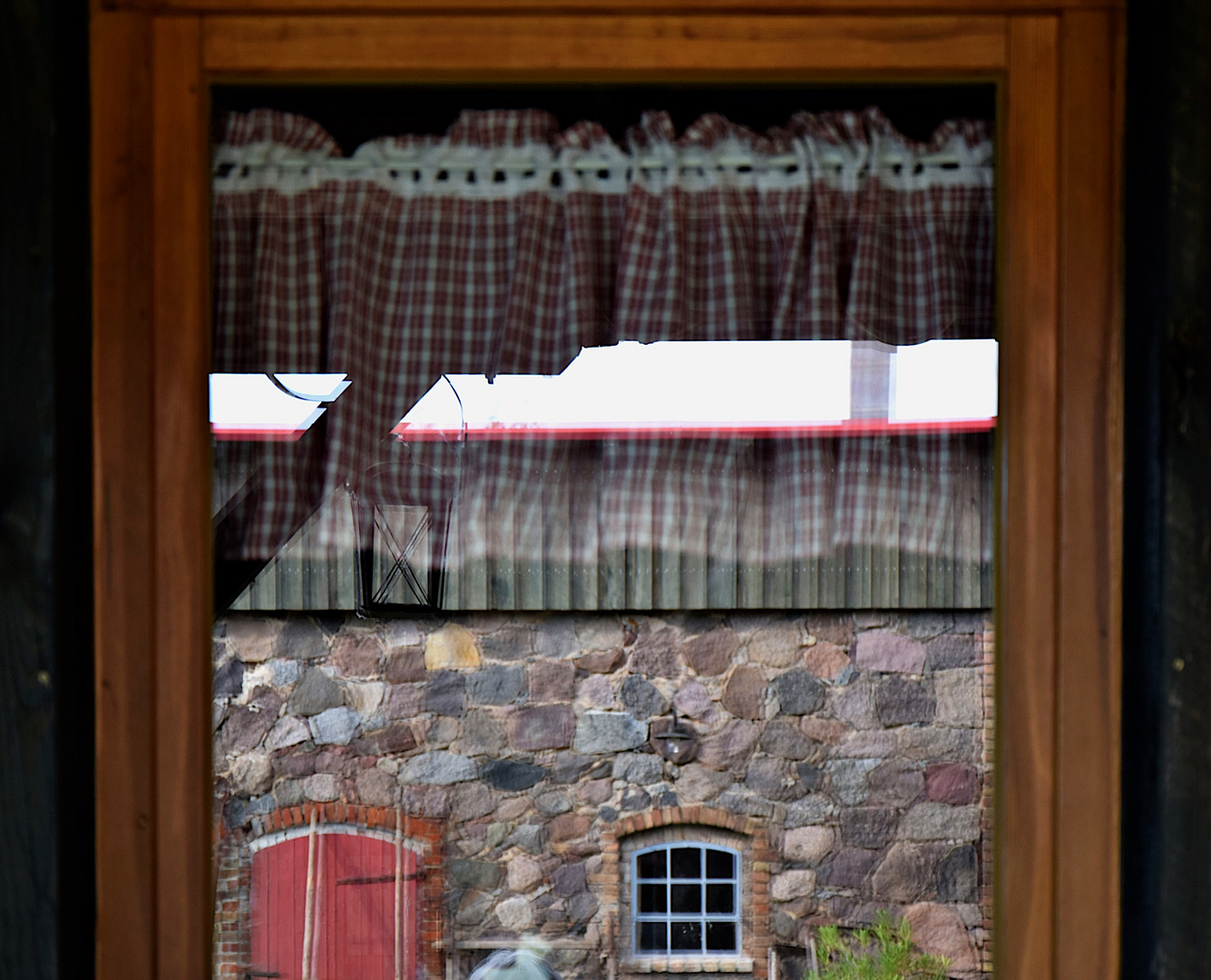 Fenster-Spiegelblick auf das Mauerwerk eines alten Nebengebäudes