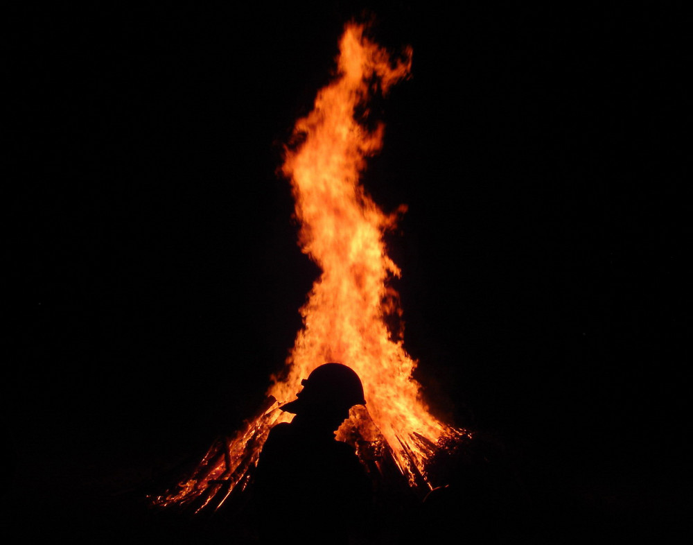 Feuerwehrmann bei einem Sonnwendfeuer