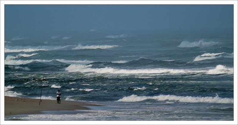 Fischer am Strand bei etwas aufgewuehlte See