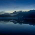 Fischer auf dem Bootssteg am Bergsee in der blauen Stunde